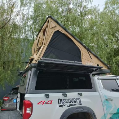 Dachzelt auf einem Pickup-Truck, umgeben von Bäumen.