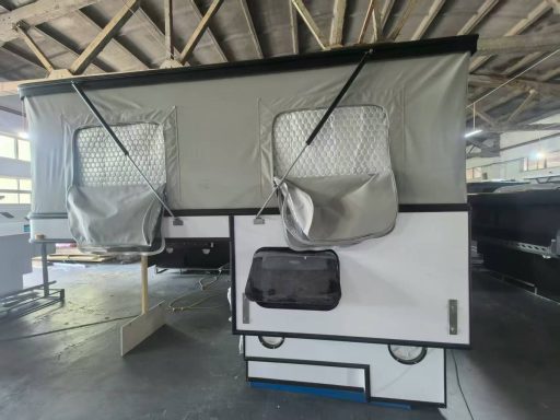 Faltwohnwagen mit zwei geöffneten Fenstern, innen in einer Halle.