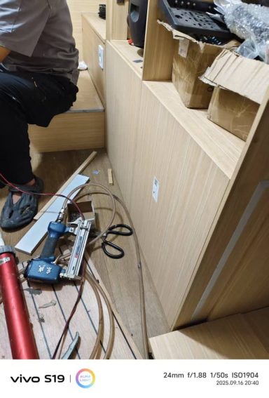 Person arbeitet in einem Raum mit Holzmöbeln und Werkzeugen auf dem Boden.