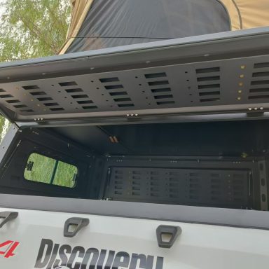 Kofferraum eines Fahrzeugs mit geöffnetem Deckel, schwarz lackiertes Innenlayout.