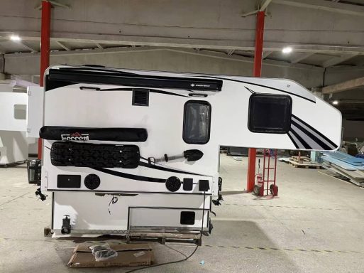 Weißer Camper mit schwarzen Akzenten, in einer Lagerhalle abgestellt.