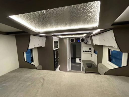 Moderne Innenansicht eines Wohnmobils mit beleuchtetem Dach und komfortablem Layout.