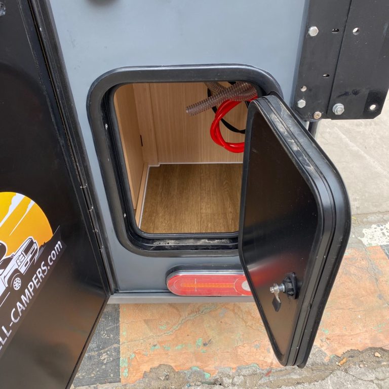 Tür eines Wohnmobils mit Zugang zu Gasflaschen und Geräten.