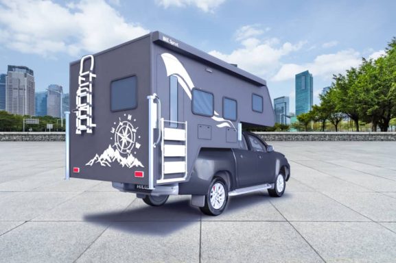 Ein schwarzes Wohnmobil mit einer erweiterbaren Dachkabine vor einer modernen Stadtlandschaft.