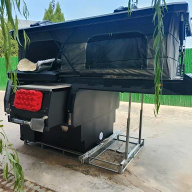 Schwarzes Wohnmobil mit aufklappbarem Dach, auf einem stabilen Gestell positioniert.