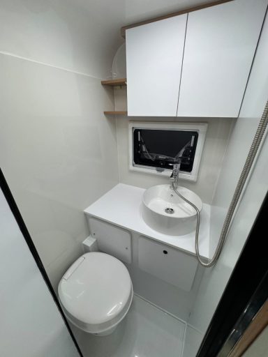 Kompakte Badezimmeransicht mit Waschbecken, Toilette und weißen Schränken.