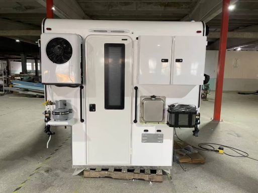 Weiße mobile Einheit mit Fenstern und verschiedenen Apparaten auf der Vorderseite.