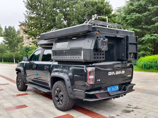 Schwarzer Pickup mit Dachzelt und Ladefläche voller Ausrüstung in städtischer Umgebung.