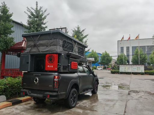 Ein gepäckter Pickup mit einem Dachzelt, parkend auf einem nassen Parkplatz.