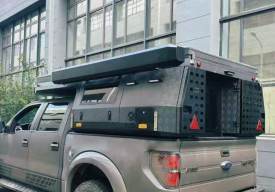 Ein grau lackiertes Pickup-Fahrzeug mit einem schwarzen, halbhoch montierten Camper-Aufbau.