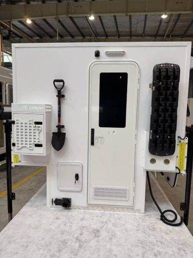 Weiße Kabine mit Tür, Fenster, Werkzeughalter und Schaufel, innen ausgerüstet.