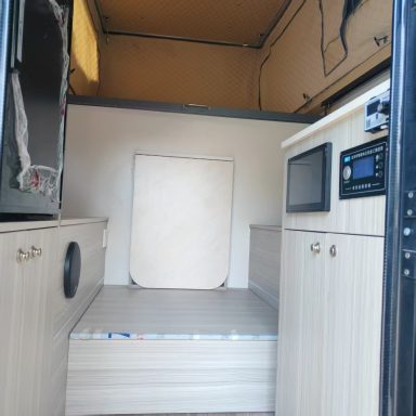 Der Innenraum eines Wohnmobils mit einem Schlafbereich und Küchenelementen.