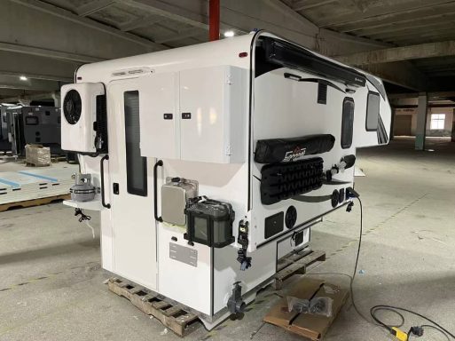 Weißer Wohnmobilaufbau auf einem Holzpalett, in einer leerstehenden Halle.