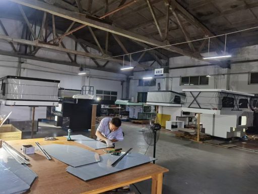 Ein Arbeiter bearbeitet Materialien in einer modernen Werkstatt mit Maschinen im Hintergrund.