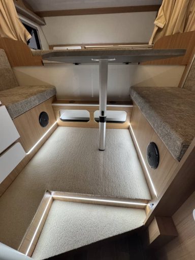 Innenraum eines Wohnmobils mit beleuchtetem Boden und Essbereich.