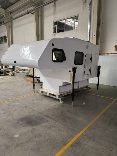 Weiße Fertigungseinheit mit großen Fenstern, auf Paletten im Innenbereich platziert.