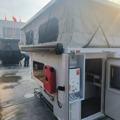 Campinganhänger mit ausgezogenem Dach, Wasser- und Stromanschluss.