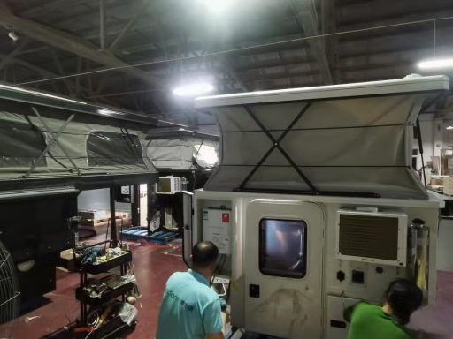 Zwei Prototypen von Wohnmobilen in einer Werkstatt, Arbeiter sind im Hintergrund sichtbar.