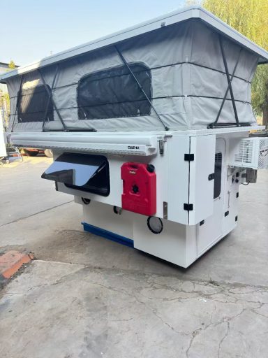 Ein weißer Campinganhänger mit klappbarem Dach und einem roten Wassertank.