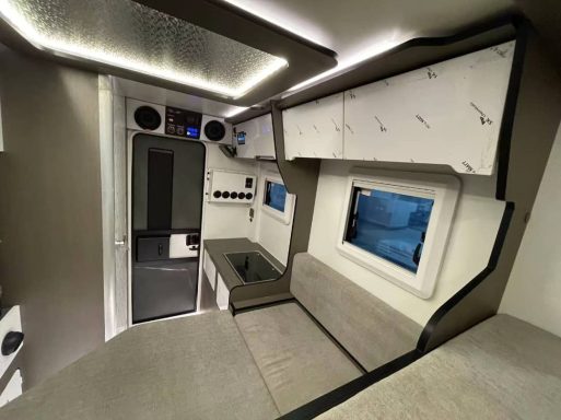 Moderne Innenansicht eines Wohnmobils mit Küche und Sitzbereich.