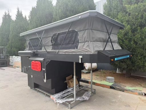 Schwarzes Wohnmobil mit aufklappbarem Dach und großen Fenstern, auf einem Parkplatz.