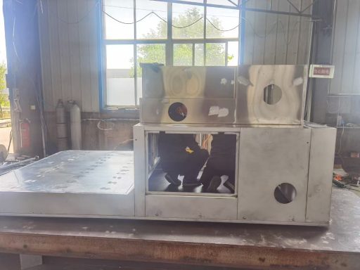 Edelstahlmaschine mit Öffnungen, auf einer Arbeitsfläche in einer Industrieumgebung.